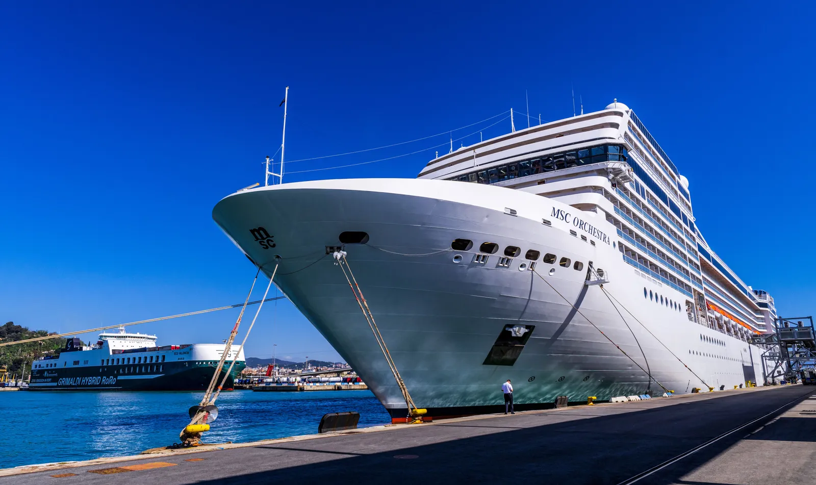 The bow of a large cruise ship moored at a quay in Barcelona port in daylight