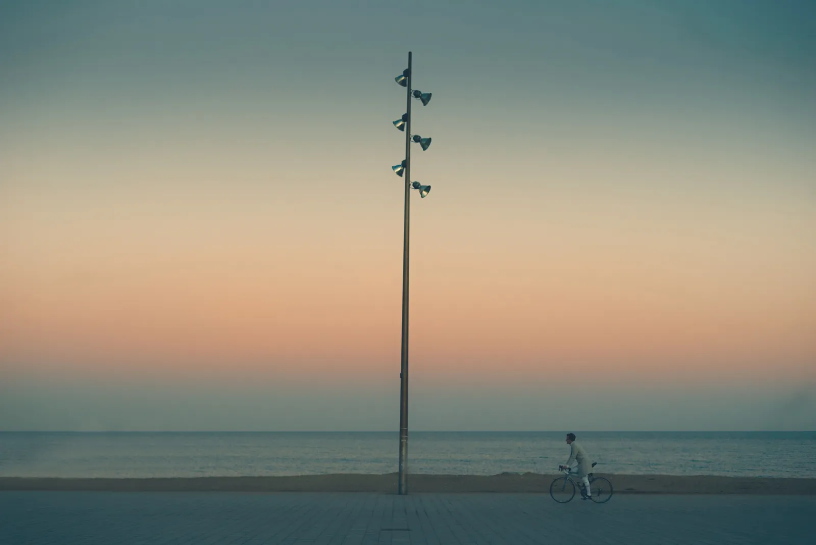 A cyclist riding the flat seafront promenade beside the beaches in Barcelona, Spain