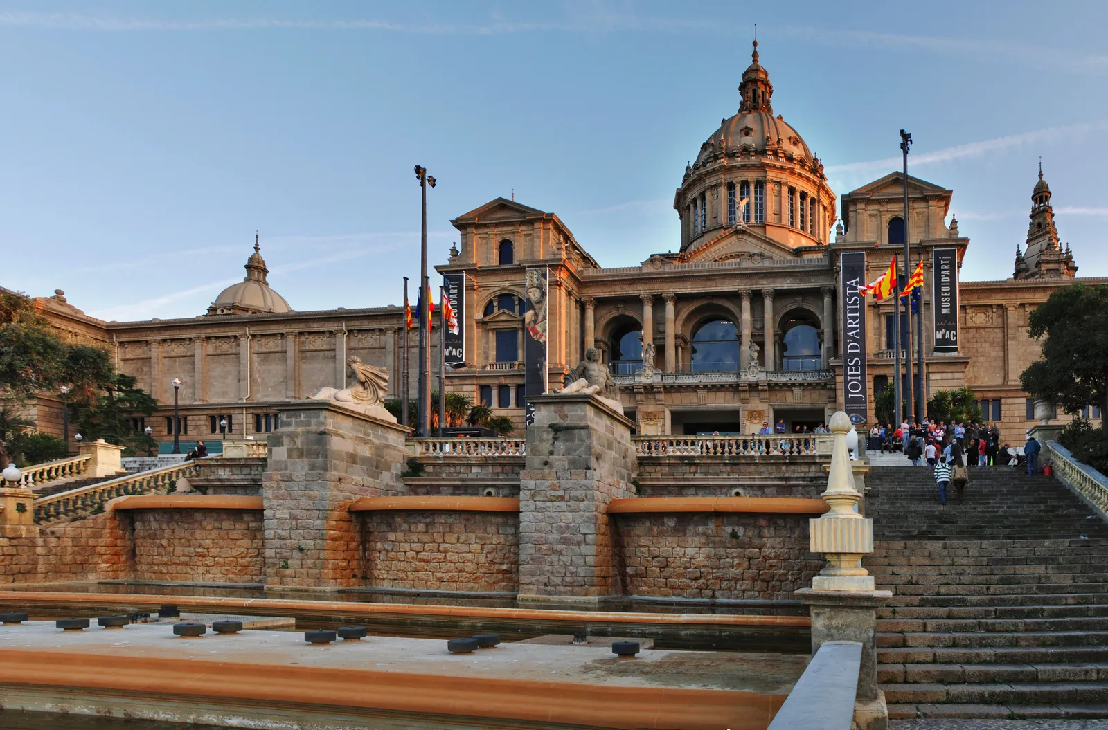 Visitors queuing at the entrance of a large museum building in Barcelona on a bright afternoon, Spain