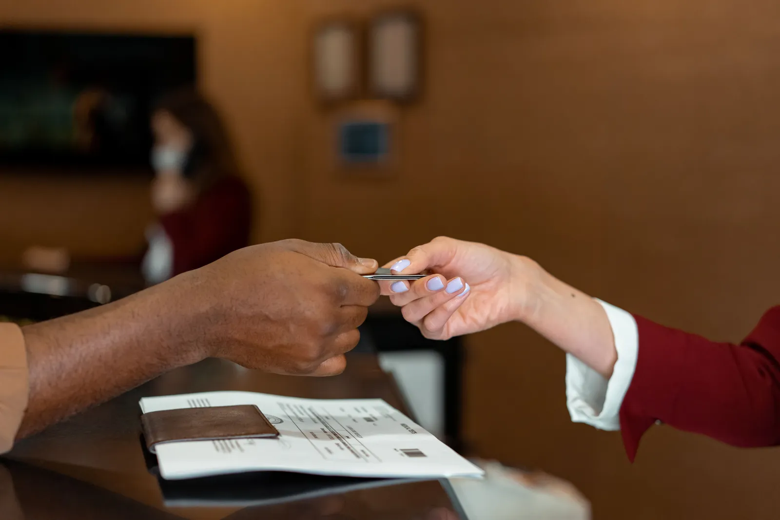 A hotel reception desk with a receptionist checking in a guest in daylight