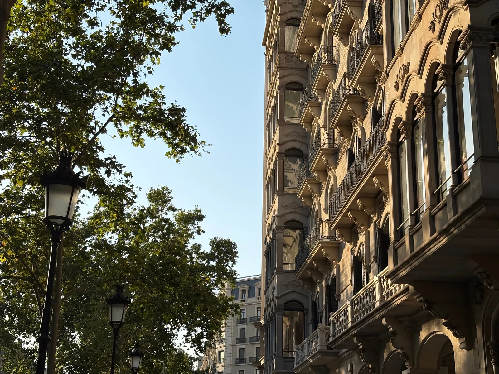 The facade of a Barcelona hotel on a tree lined Eixample street in daylight