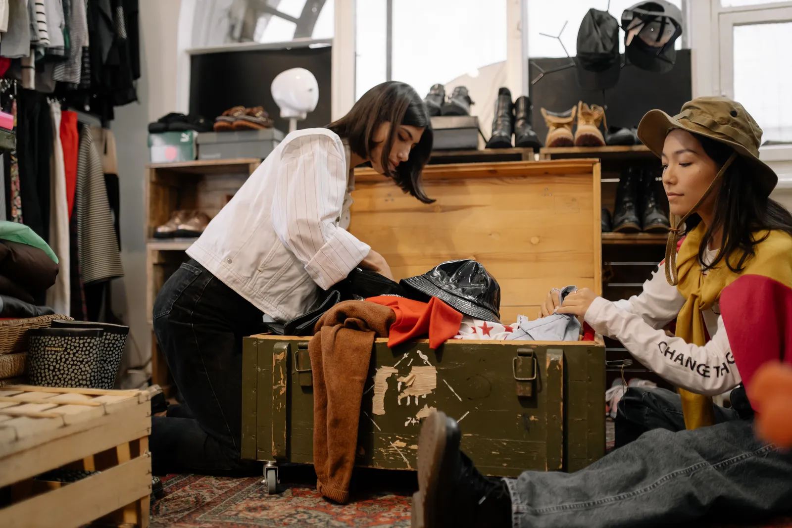 A woman sorting through clothes and vintage cases inside a second hand shop