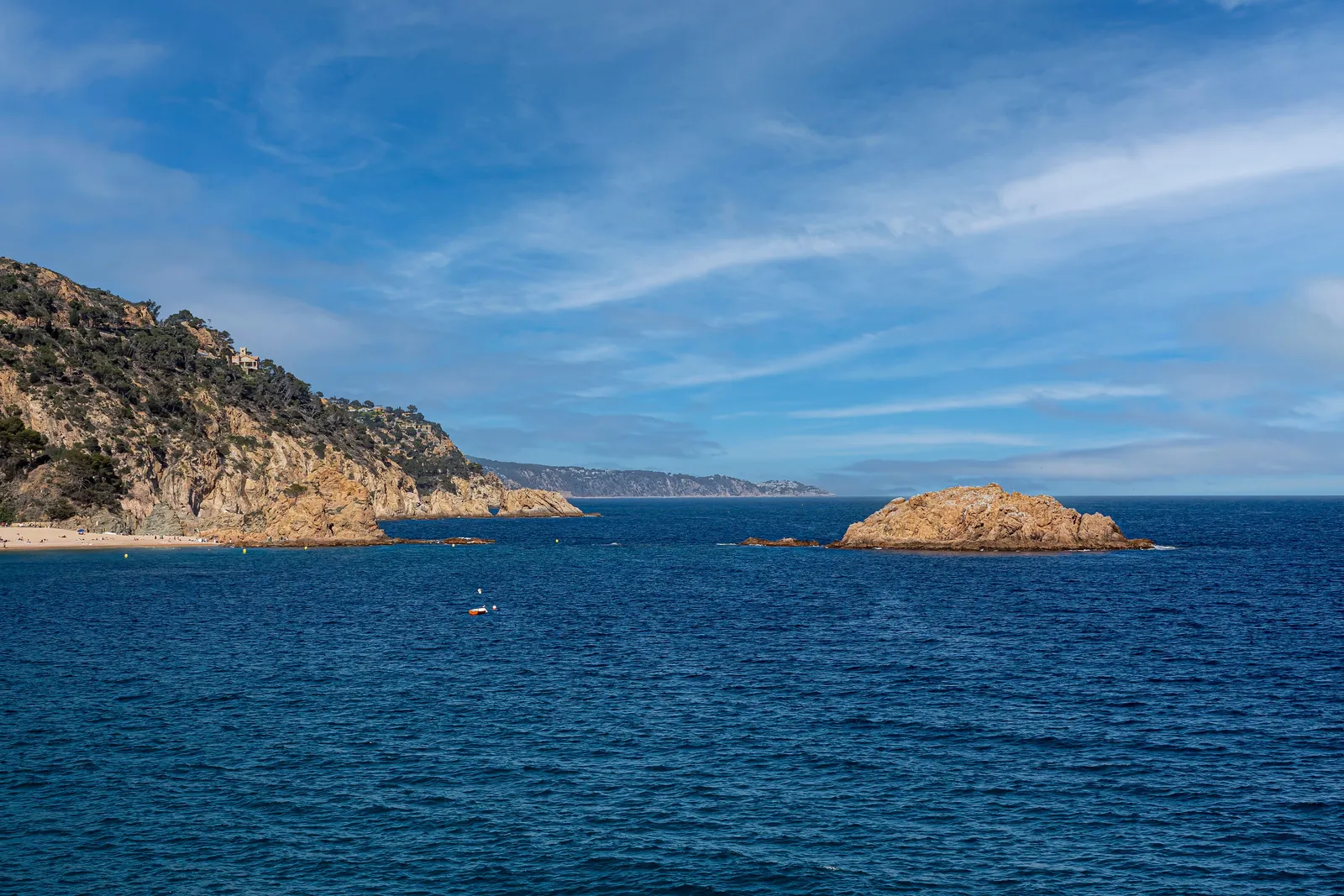 The rocky Mediterranean coastline north of Barcelona seen from the shore in summer daylight