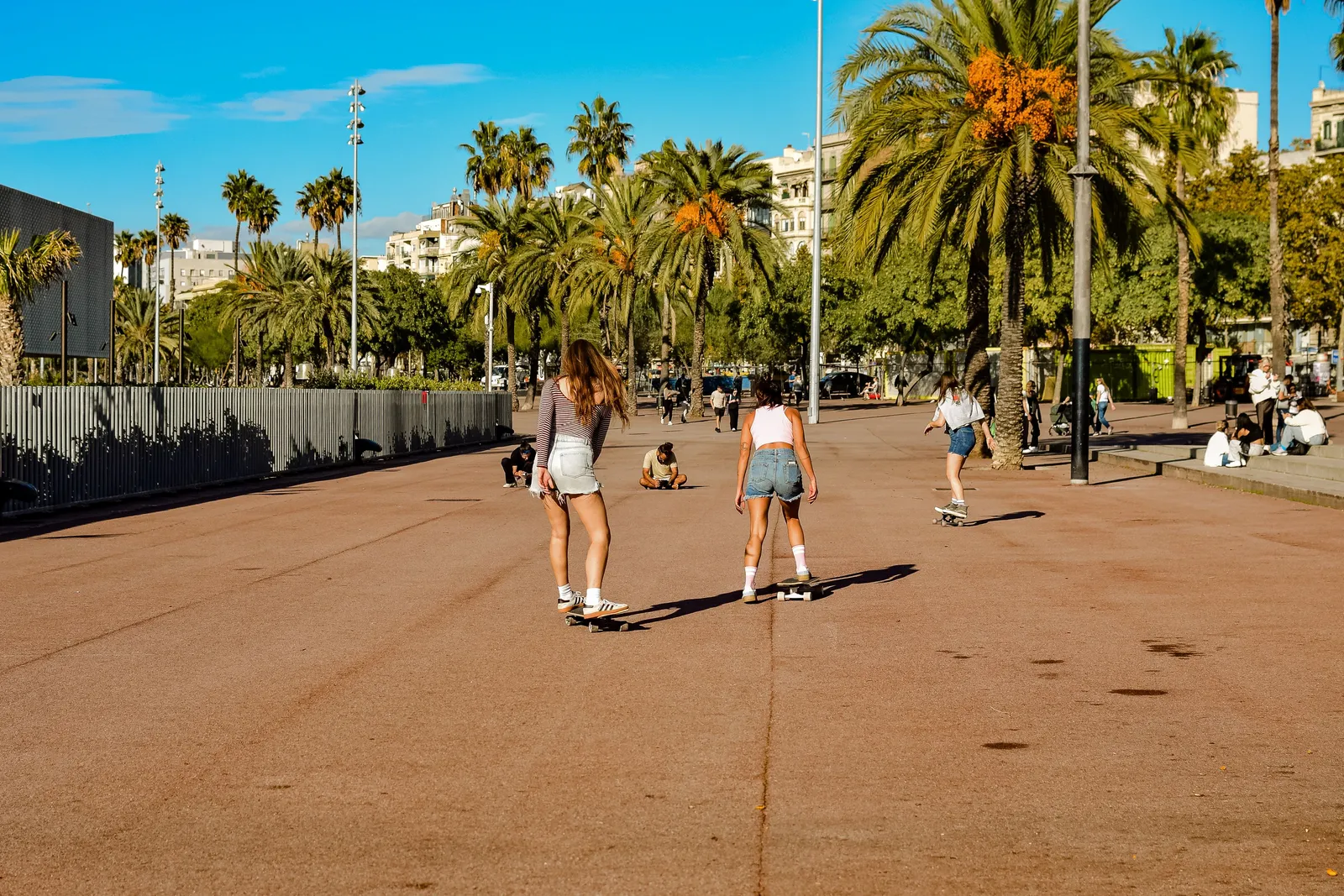 Skateboarders and onlookers on the open pavement of a large city plaza in Barcelona, Spain