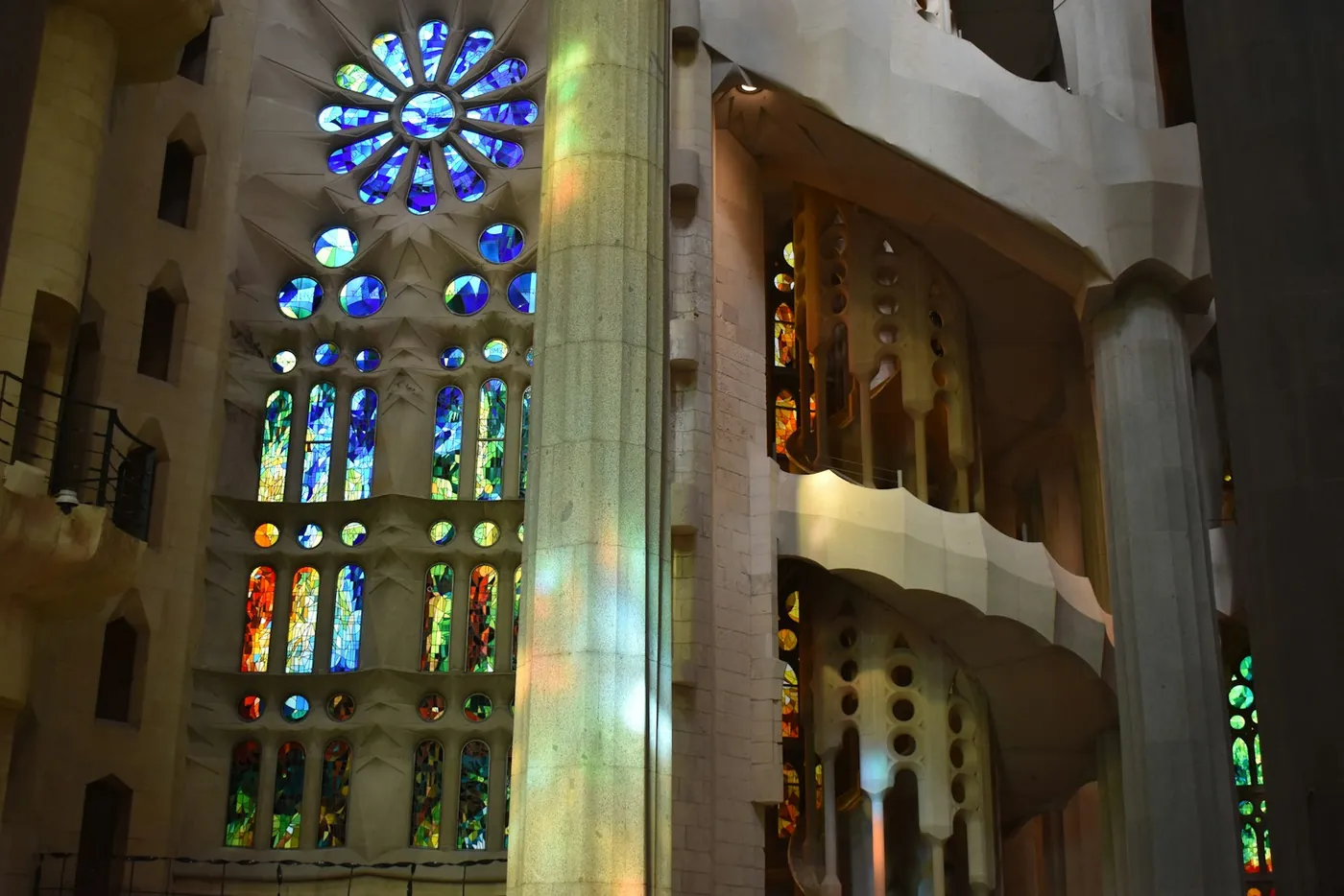 The interior nave of the Sagrada Familia in Barcelona with branching stone columns and coloured light from stained glass windows