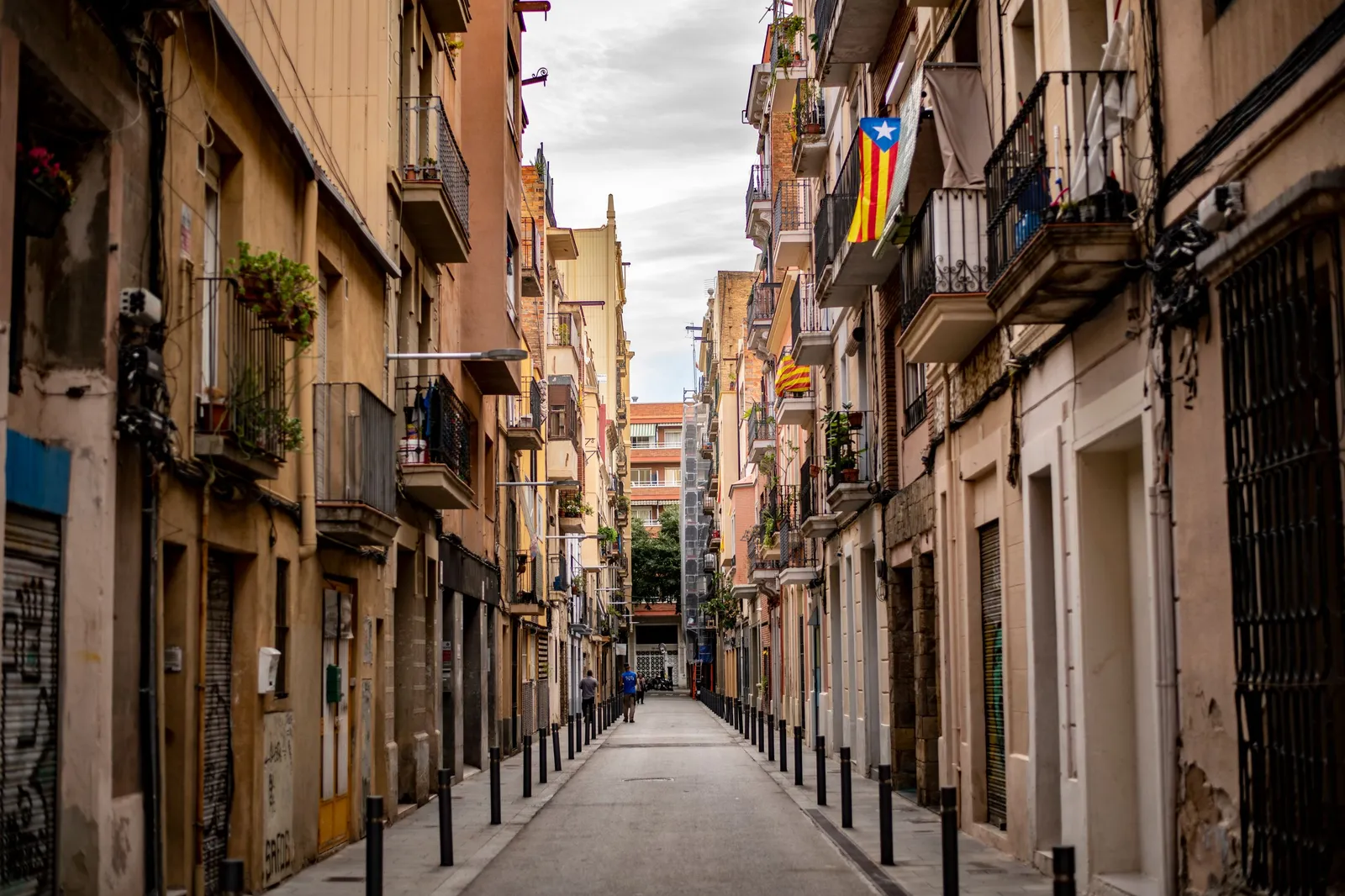 A narrow street of small independent shopfronts in the Gracia neighbourhood of Barcelona, Spain