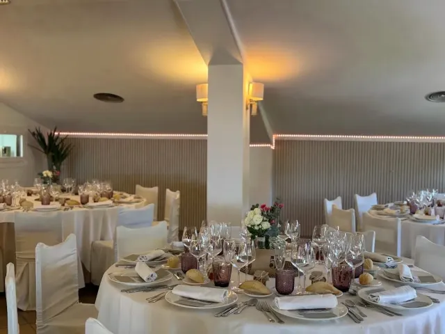 An event hall with round tables in white, many glasses and chair covers