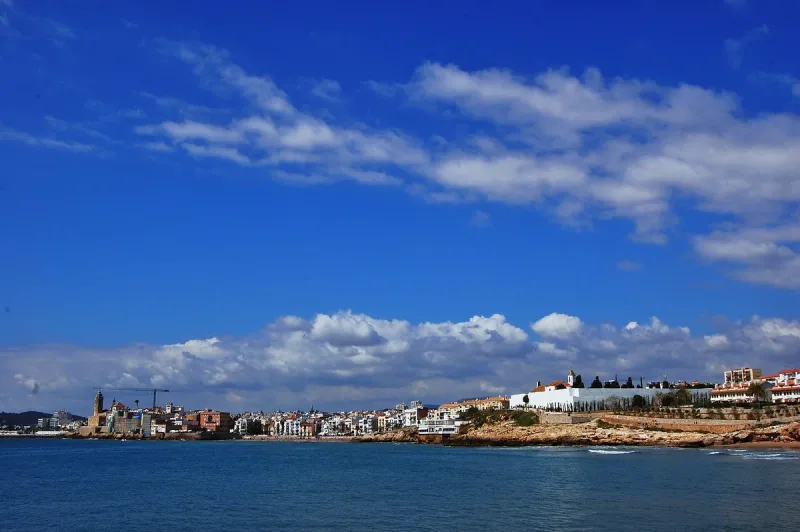 Blue bay with a rocky shore and a white coastal town on the horizon