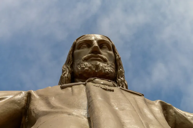 Gilded statue of Christ with outstretched arms against the sky