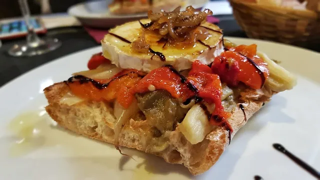 A slice of toasted bread with roasted peppers, goat cheese and caramelised onion on top