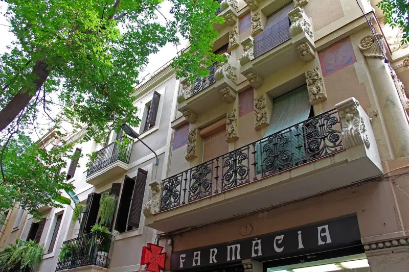 Narrow street with iron balconies and a pharmacy sign on a shopfront