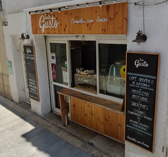A small wooden storefront with written chalkboards and a display window of pastries