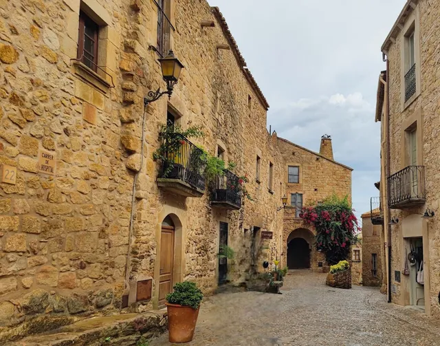 A cobbled lane between old stone houses, with iron balconies and blooming bougainvillea