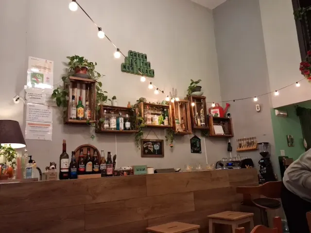 A light wooden counter, hanging crates with bottles and plants and a string of bulbs