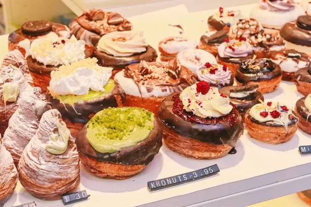 A tray full of pastries glazed with chocolate and cream, with small price labels