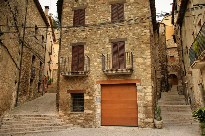 A paved lane between medieval stone houses, with stepped alleys climbing on both sides