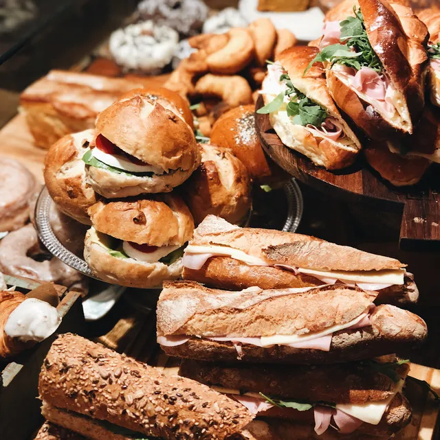 Baguettes with ham and cheese and filled rolls, piled on wooden trays