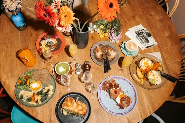 An overhead view of a round table with breakfast dishes, orange flowers and glasses