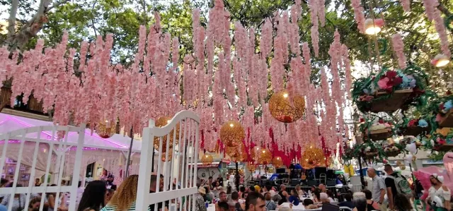 Hanging pink flower decorations above a large crowd on a decorated street