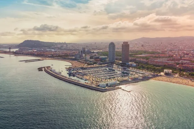 An aerial view of a marina full of boats, two tall towers and a curving beach