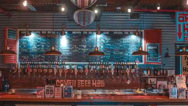 A bar with a long row of taps and chalkboard menus above, a corrugated metal wall