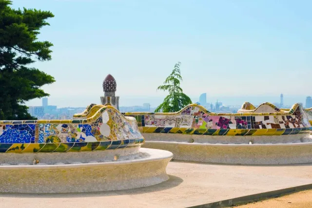 A winding bench clad in colorful ceramic shards, with a hazy skyline behind