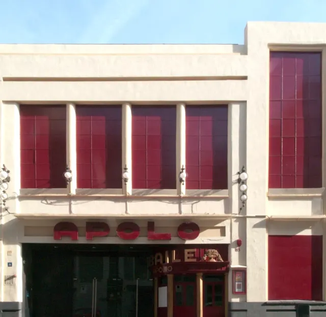 A pale facade with crimson panels and red letters above the entrance