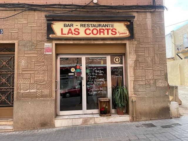 The stone frontage of a neighbourhood bar restaurant, with a wooden sign and a menu written on the glass
