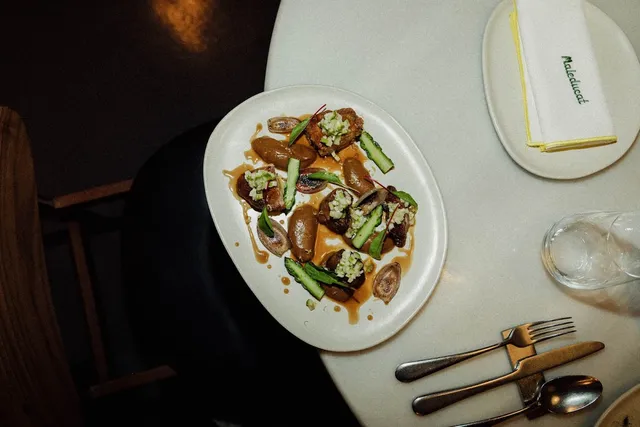 A plated dish with green vegetables and brown sauce on a white plate, seen from above