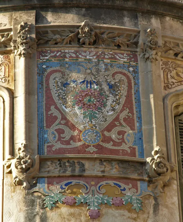 A colourful mosaic panel with a floral wreath between carved stone pilasters