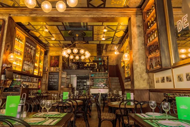 An old style dining room with a painted ceiling, chandeliers and lit bottle shelves