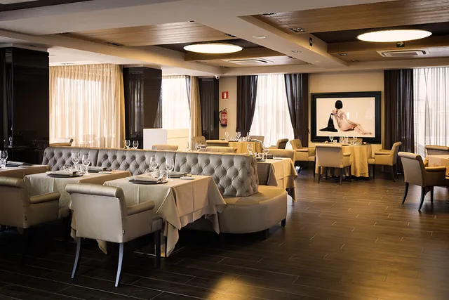 A spacious dining room with pale upholstered sofas and tables set with white cloths