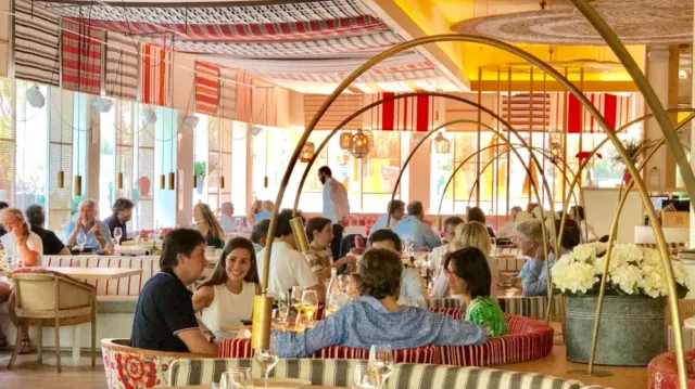 A bright hall with golden arches, colorful striped upholstery and many diners