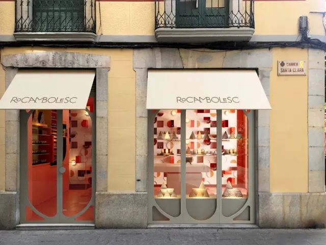 A shopfront with two pale awnings and a pink window full of cones