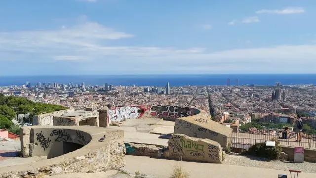 Concrete remains covered in spray writing on a hilltop, with a wide view over the city and the sea