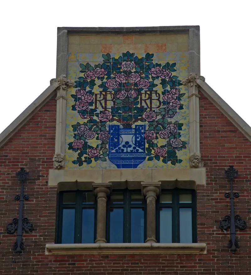 Ceramic panel of roses and a city crest on a red brick gable