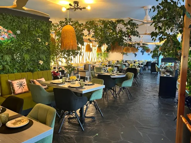 A hall with a green plant wall, a mustard bench and velvet chairs around tables
