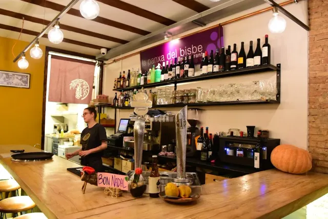 A pale wooden counter with a coffee machine, shelves of bottles and an orange pumpkin at the end