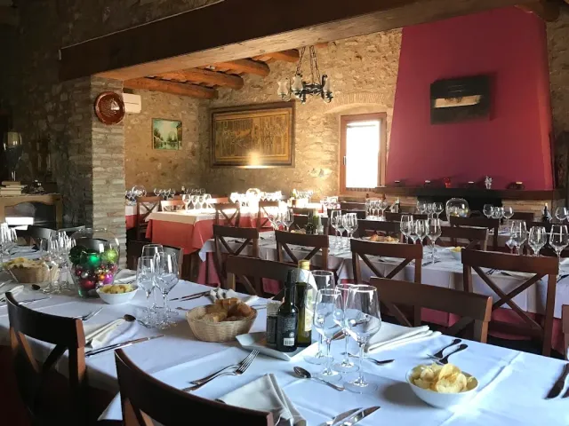 A rustic hall with stone walls and wooden beams, set tables and a framed picture