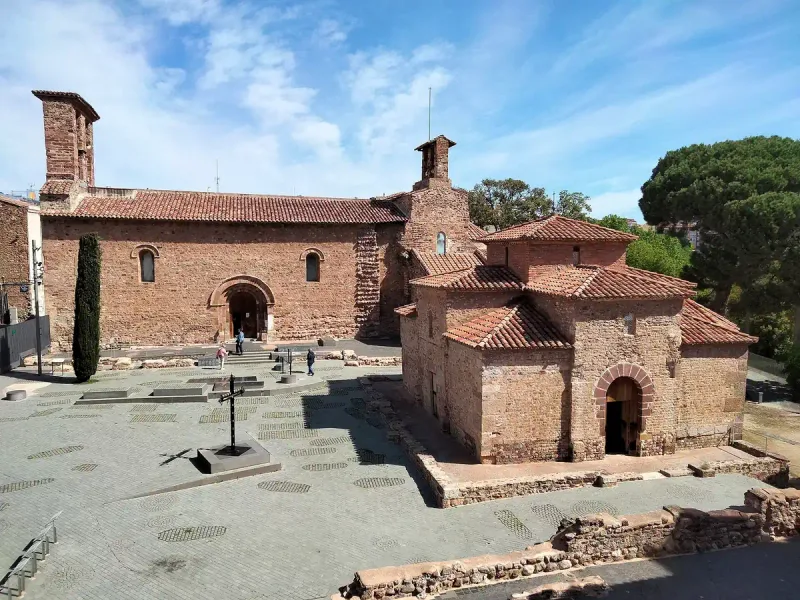 Two Romanesque stone churches with tiled roofs and a paved forecourt