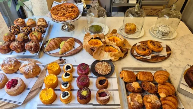A marble counter loaded with croissants, tarts and cakes covered by glass cloches