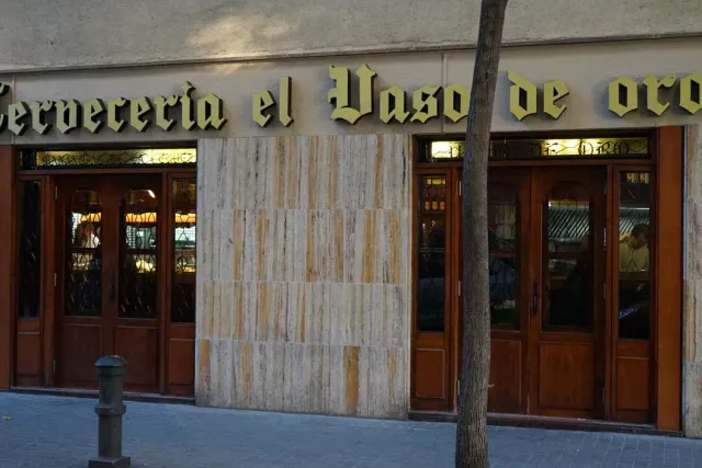 A shopfront with large gold letters and two wooden doors set with glass