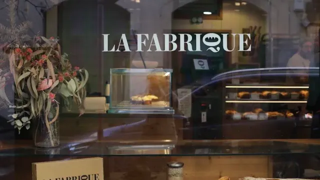 A display window with white lettering, a dried flower bouquet and pastries in the case