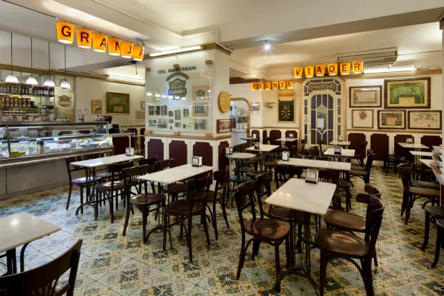 An old cafe hall with marble tables, wooden chairs and a patterned mosaic floor