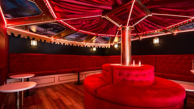 A red velvet lounge under a carousel style canopy with strings of lights