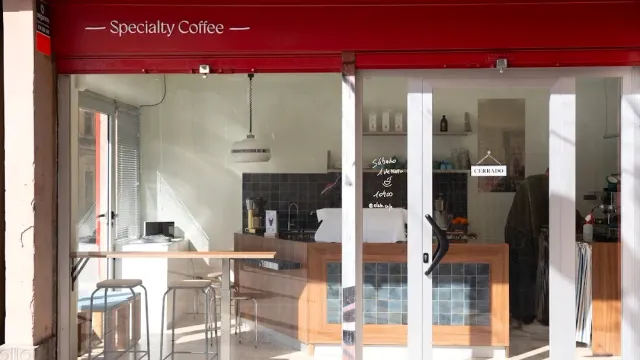 A glass front with a red canopy, and inside a counter, stools and a chalkboard