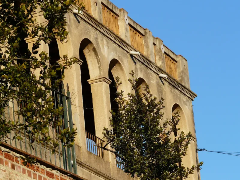 Rendered country house facade with a row of arched windows and trees in front