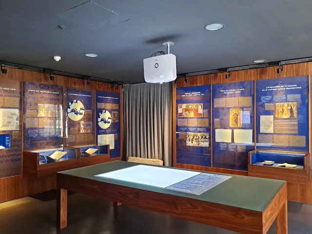An exhibition room with blue information panels, display cases and a wooden table at the center