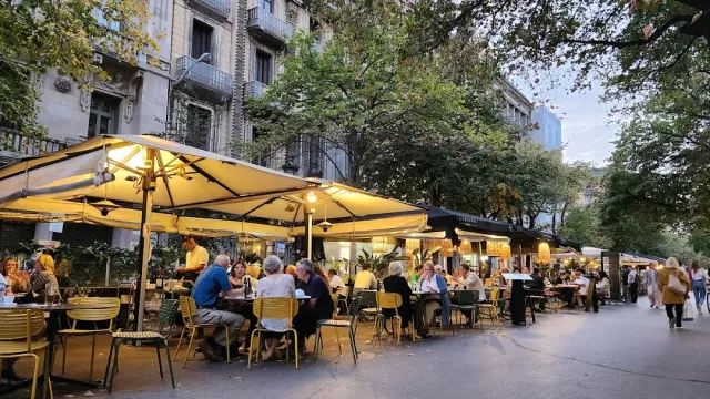 A row of lit yellow parasols with many diners at dusk