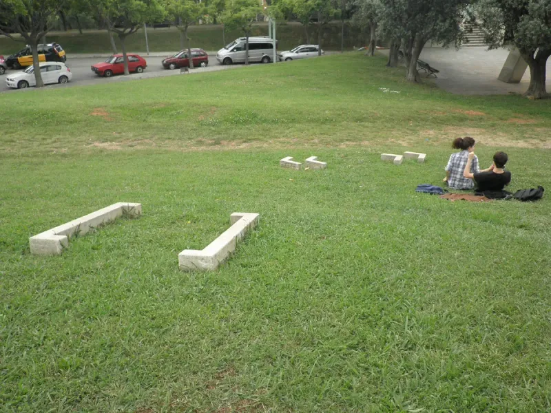 Green lawn with white stone benches and people sitting on the grass